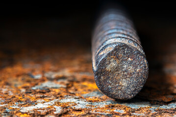 Ribbed reinforcing bar close-up, on a corroded steel surface