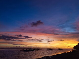 Vibrant Tropical Sunset with Traditional Boat Silhouettes