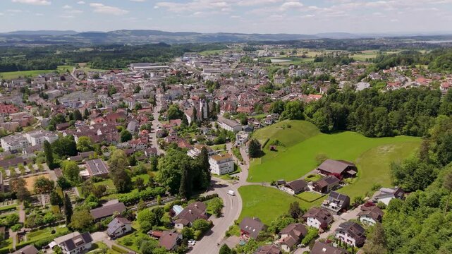 Main street of Hinwil City in Switzerland during sunny day. Aerial wide shot. Luxury houses with solar panels on roof. Swiss town in summer.