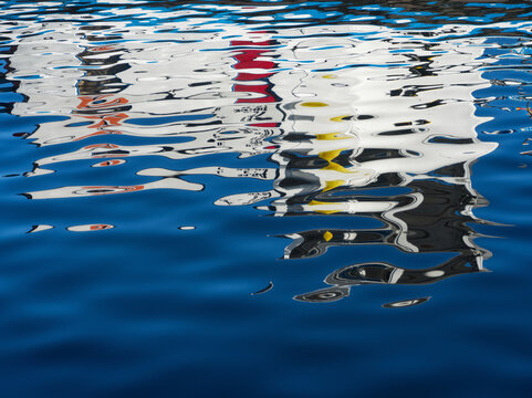 Blue water reflex background. Abstract reflection and abstract inspection elements in water. City, buildings, house elements distorted in the river. Rippled water texture. Disordered water surface.