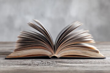 Beautifully opened book displaying pages in motion on a rustic wooden table background during daylight hours