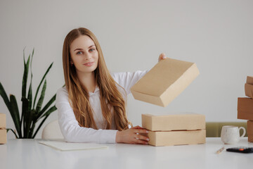 Young woman arranging cardboard boxes on a table in a bright workspace during daylight hours