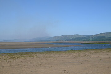 a view of the river Dovey from ynyslas beach with the smoke from a wild fire close to Machynlleth in the background 
