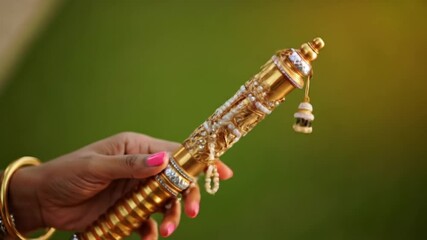 Krishna Janmashtami womans hands with gold and diamondencrusted ceremonial staff. Suitable for festive backgrounds, religious designs, cultural celebrations.