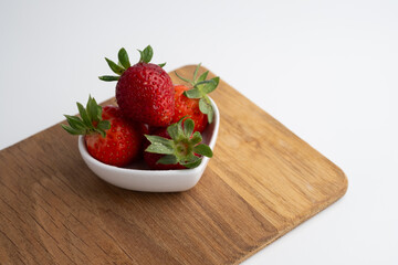 Ripe strawberries on a heart-shaped plate on a light background. Healthy food.