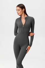 Fitness woman in jumpsuit. Athletic girl on the gray background