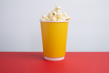 Delicious popcorn in a bucket on a red background. Tasty snack