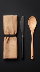 Folded Apron Beside Kitchen Towel and Wooden Spoon on Dark Background