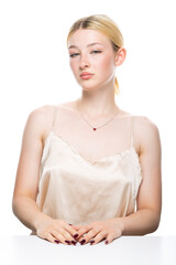 A young blonde girl with freckles in a golden top. Beauty portrait of a woman on a white background in the studio.