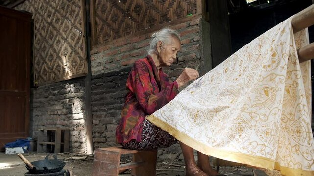 Elderly indonesian woman making traditional batik