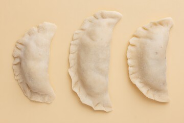 Uncooked pierogi three pieces pale background