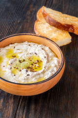 Creamy baba ghanoush in wooden bowl with chili and olive oil