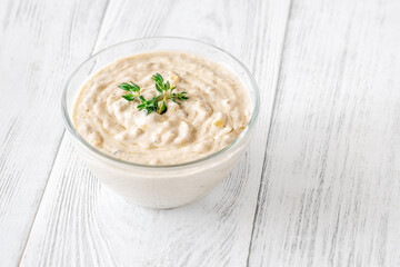Creamy blue cheese sauce garnished with thyme in clear bowl on table