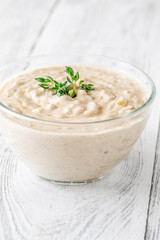 Creamy blue cheese sauce garnished with thyme in clear bowl on table