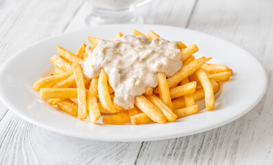 Golden fries drizzled with rich blue cheese sauce on white plate
