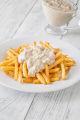 Golden fries drizzled with rich blue cheese sauce on white plate