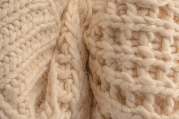 A fragment of beige knitted fabric, knitted from white sheep wool.