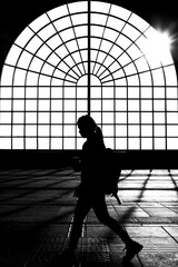 Silhouette of a person walking by a big window in backlight