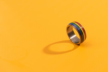 LGBT Badge accessory on a rainbow background.