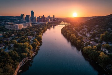 Naklejka premium Beautiful sunset over city skyline and calm river with green trees along the banks