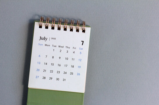 A desktop calendar for July 2025 on a desk with space to copy.