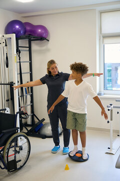 Patient practices balancing on one foot while therapist provides support