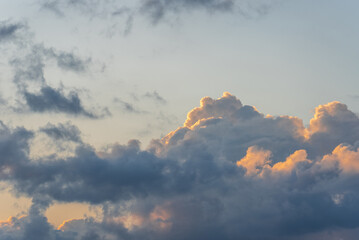 beautiful gray-blue cumulus clouds with orange tops illuminated by the sun, the mood of summer relaxation and travel