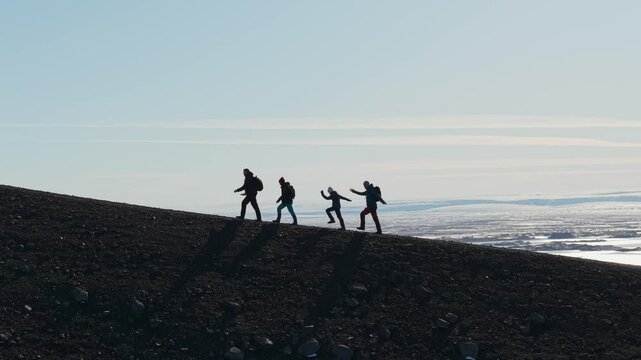 Tourists are happily and joyfully climbing the mountain. A group of tourists climbs the volcano Hverfjall in Iceland. Tourism, expedition, travel and adventure concept.