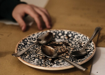 a dirty plate of food with cutlery and the hands of a child busy eating the meal in an Italian house during lunch time