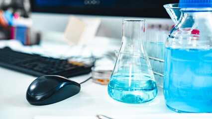 Glass labware with blue liquid in a modern science laboratory, representing chemical research, technology, and scientific experiments in a controlled environment.