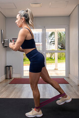 46 year old Brazilian woman doing resistance band exercises for the outer thighs_vertical.