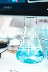 Glass labware with blue liquid in a modern science laboratory, representing chemical research, technology, and scientific experiments in a controlled environment.