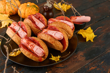 Halloween background. Homemade hot dogs with bloodied fingers on dark table for Halloween. Themed food for celebration party Halloween. Copy space.