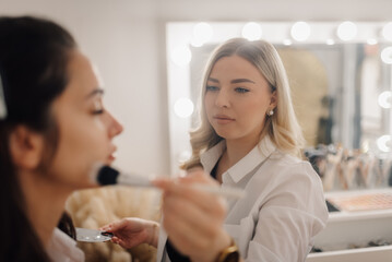 Makeup artist applying foundation on model's face in beauty salon