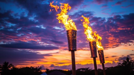 Obraz premium Enjoy the mesmerizing dance of fire from tiki torches as the sun sets.