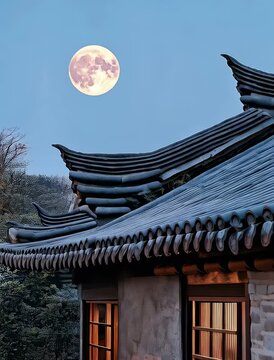 Beautiful night view of a traditional house under the full moon with blooming flowers in the foreground in a serene garden setting