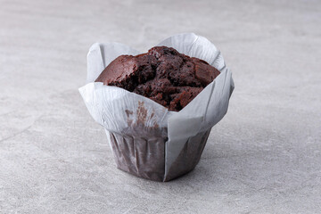 Chocolate Muffin in Tulip Paper Cup on Gray Stone Background