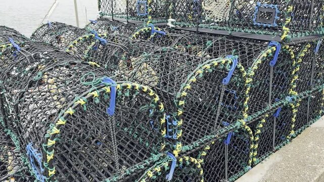 Closeup slow crane shot of mesh lobster and crab pots (also called D creels) stacked in layers, in a UK harbour quay.