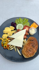 Healthy breakfast of scrambled eggs, sausage, cheese, salad, vegetable, and tomato