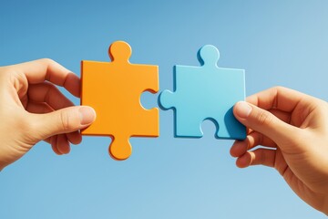 Two hands holding orange and blue puzzle pieces fitting together against a clear blue background symbolizing business teamwork and creative cooperation.