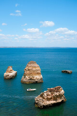 16 June 2016 - Lagos, Portugal: aerial view of a man steering a dinghy between sea stacks. Person on a boat at sea. Bright summer day in the Algarve.
