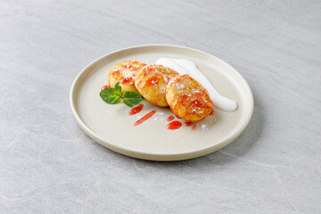 Cottage Cheese Pancakes Syrniki with Strawberry Sauce and Sour Cream on Beige Plate