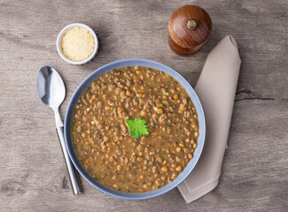 Lentil soup in a bowl with seasoning over stone background