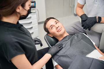 Nice brunette woman dentist calming down patient before teeth check-up
