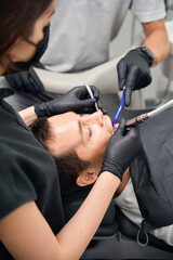 Team of dentist treating male client teeth, drilling and installing fillings