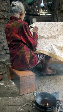 Elderly indonesian woman creating traditional batik