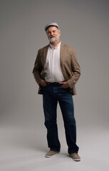 Full length body size view of attractive serious grey-haired man in suit and flat cap isolated on grey