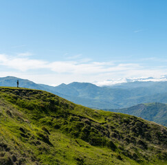 Solitary man standing on green hilltop in Ismayilli, Azerbaijan looking at the Greater Caucasus Mountains.