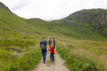 Obraz premium Happy children with parents and dog, european family, hiking the Kvalvika trail on hill at Kvalvika beach, Norway