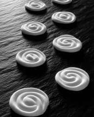 White sugar arranged into spiral patterns on a dark slate
